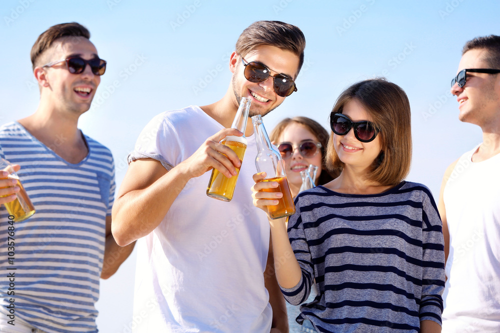 Young people with beer on the riverside