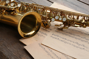 Sticker - Beautiful golden saxophone with musical notes on wooden background, close up