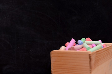 Wall Mural - Wooden box of coloured chalk in front of blackboard