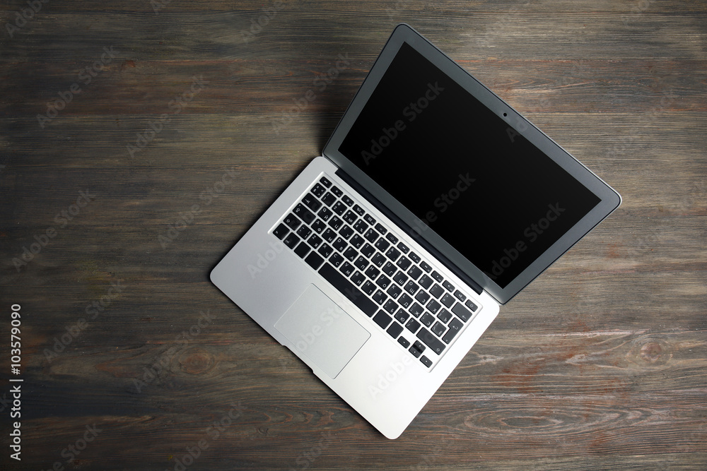 An open silver laptop on the wooden background