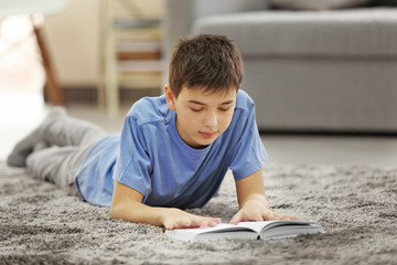 Boy reading book on a floor at home