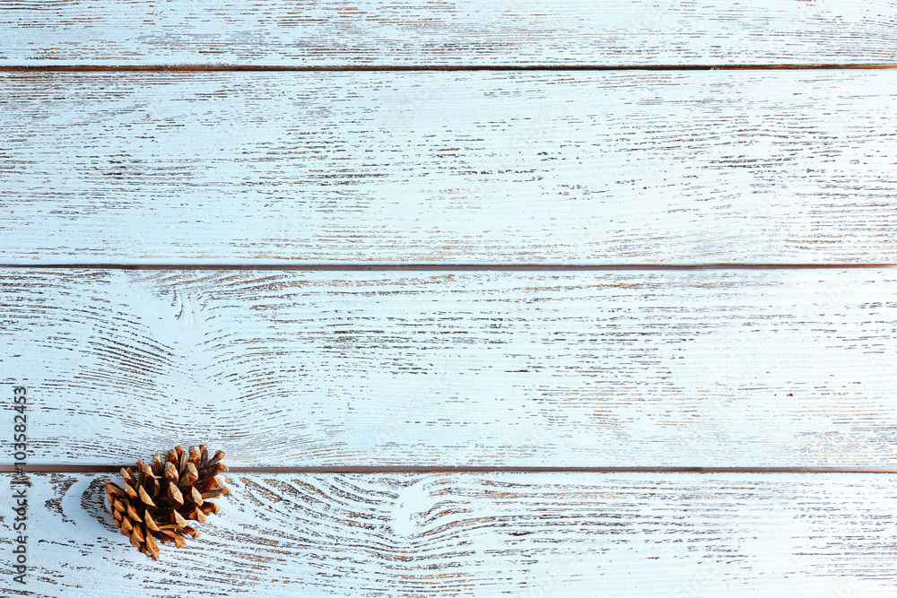 Beautiful simple winter background with pine cone on wooden texture