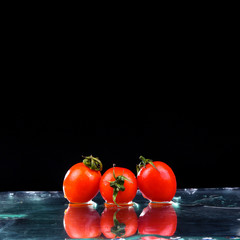 Studio shot with freeze motion of cherry tomatoes in water splash on black background with copy space