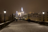 Fototapeta  - Night snowy Prague gothic Castle, Bridge Tower and St. Nicholas' Cathedral from Charles Bridge with its Statues, Czech republic