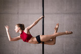 Beautiful woman performing pole dance. Shot with industrial concrete background.