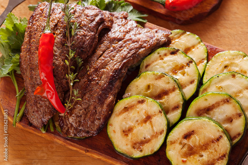 Naklejka dekoracyjna Delicious beef steak with vegetable over wooden table close-up