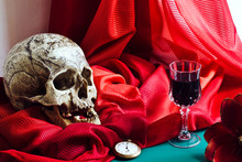 Still Life With Skull In The Style Of Vanitas With Artistic Retouching. Skull, Glass, Watches, Flower On A Background Of Red Drapes.
