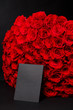 Romantic bouquet of luxury 101 red roses with a black card blank for  logo, on black studio background, spring is on 8 March, International Women's Day