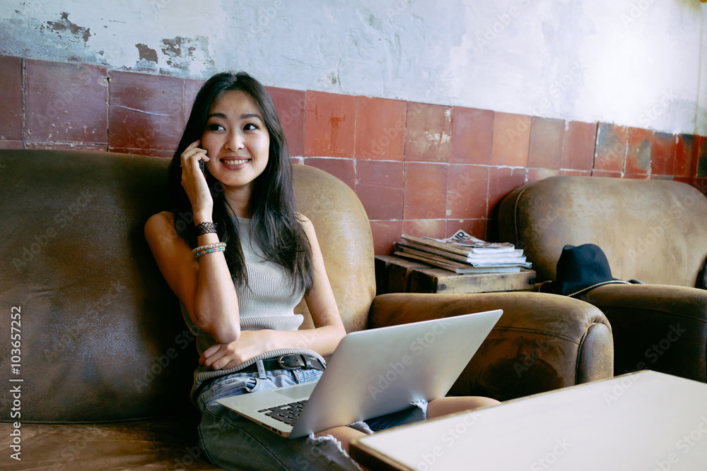 young beautiful Asian female student working with a laptop in a cafe ...