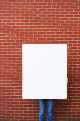 blank board held ready for text in front of brick wall