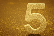 Number five golden color over a warm background. Anniversary