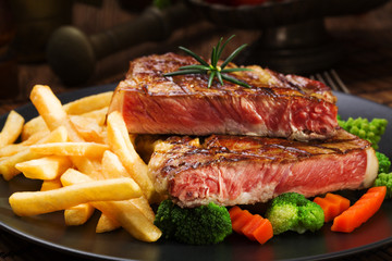 Grilled beef steak served with French fries and vegetables on a