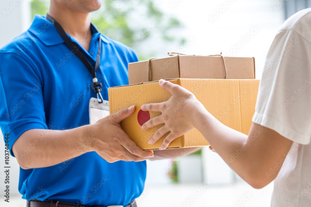 Woman hand accepting a delivery of boxes from deliveryman - obrazy, fototapety, plakaty 
