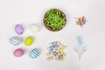 Wall Mural - Easter eggs, basket, and candy on a white background