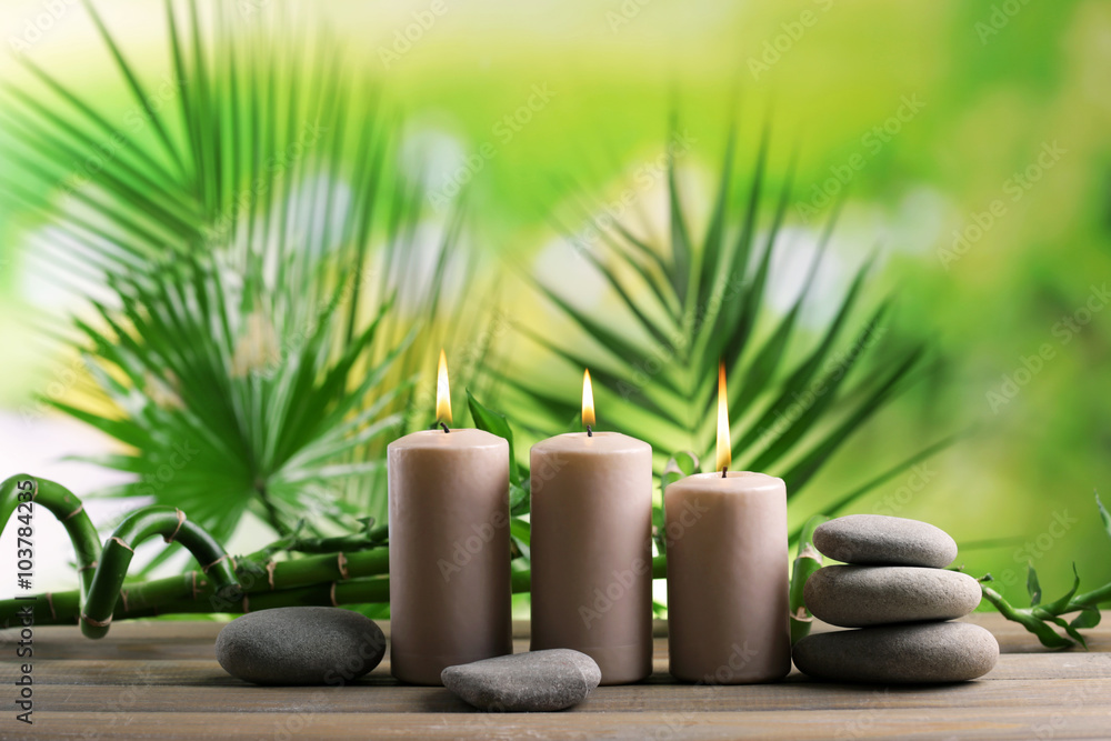 Spa composition of candles, stones and bamboo on blurred background