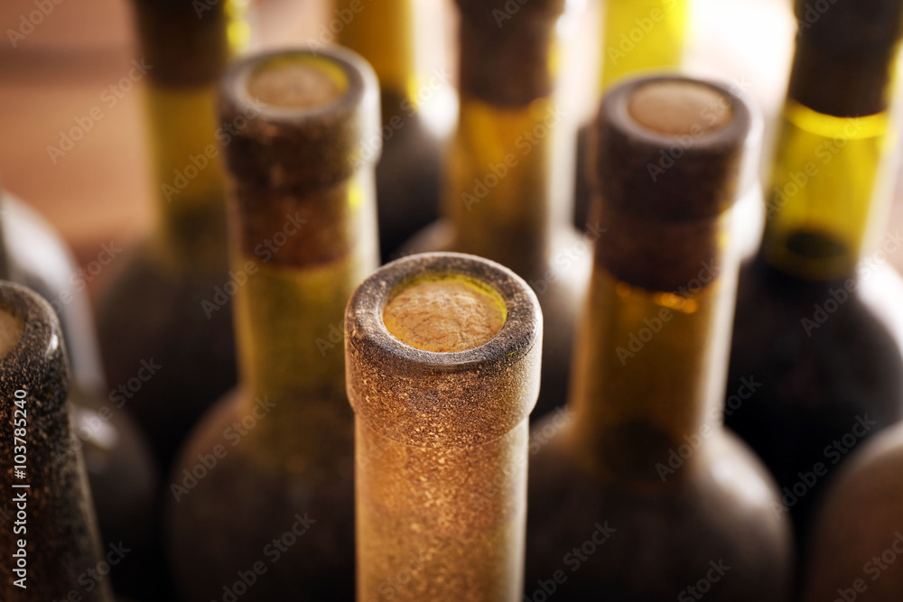 Stacks of dusty wine bottles on wooden background, upside view. Close up