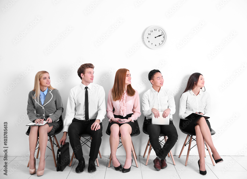Young people sitting on a chairs and looking left in white hall