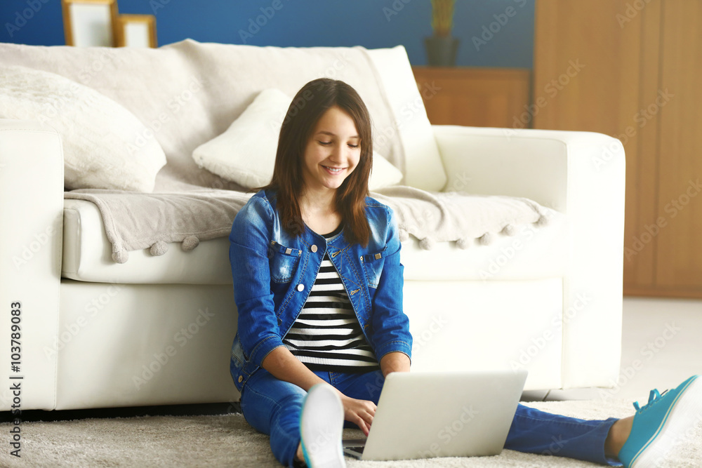 Beautiful girl with laptop on carpet indoor