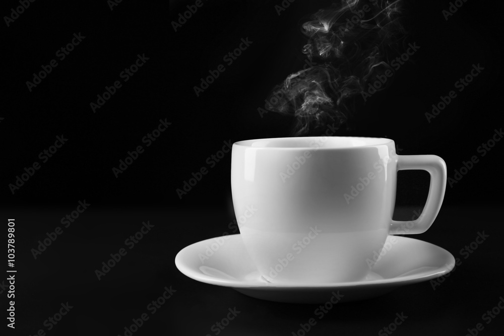Hot tea in white cup on black background, close up