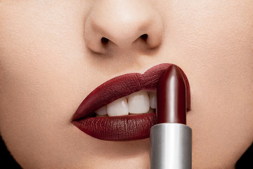 Woman applying red lipstick on lips