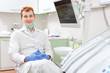 © kulniz - Portrait of happy and smiled young male dentist sitting in chair of dental clinic