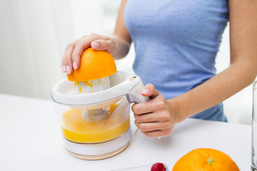 Wall Mural - close up of woman squeezing orange juice at home