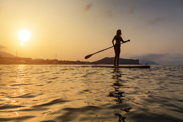 Wall Mural - Silhouette of a beautiful woman on Stand Up Paddle Board. SUP.