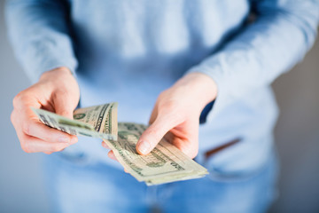 Female hands counting US Dollar bills or paying in cash. Shallow DOF.