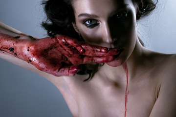 Beautiful portrait of young brunette woman with bloody hands. Ho