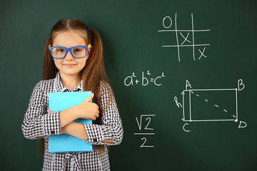 Beautiful little girl  near blackboard in classroom