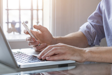 Young man working from home with laptop computer and smartphone