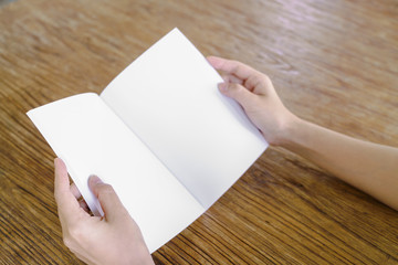 Hands open book on wood table