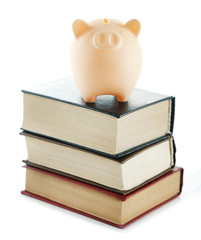 Poster - Piggy bank on top of books isolated on white