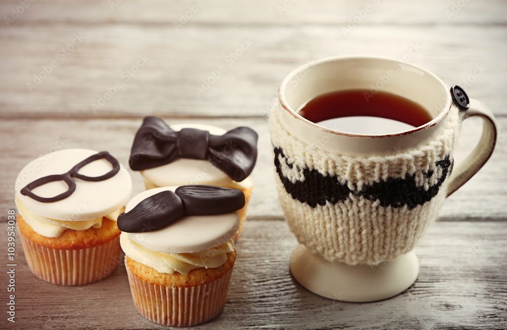 Delicious creative cupcakes and cup of tea on wooden table