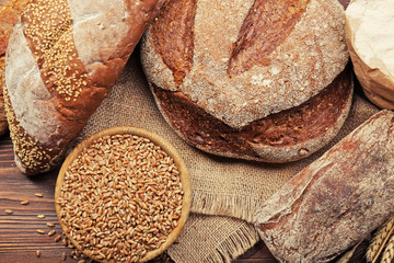 Canvas Print - Fresh baked bread and a bowl of wheat grains on the wooden background