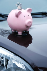 Poster - Piggy money box with cash and key on car bonnet at the street