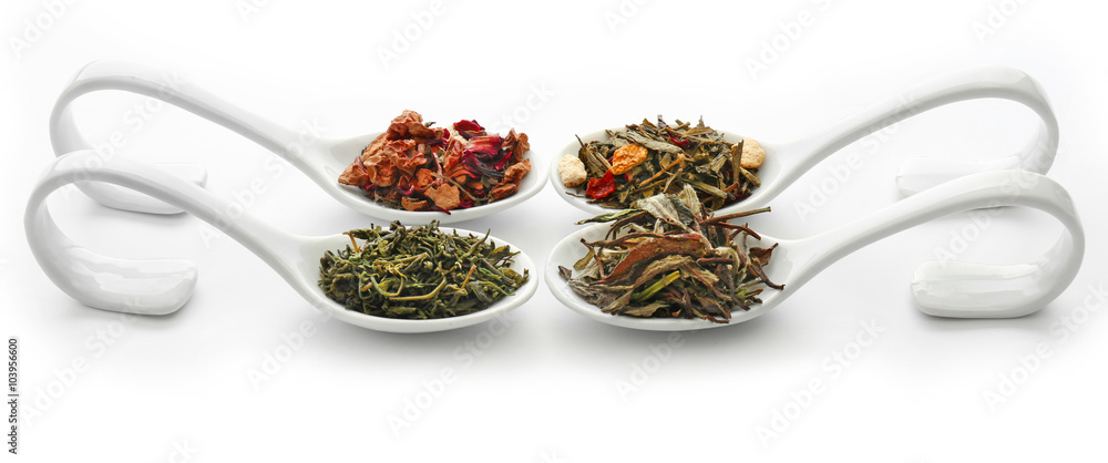 Different sorts of dry tea in ceramic spoons, isolated on white