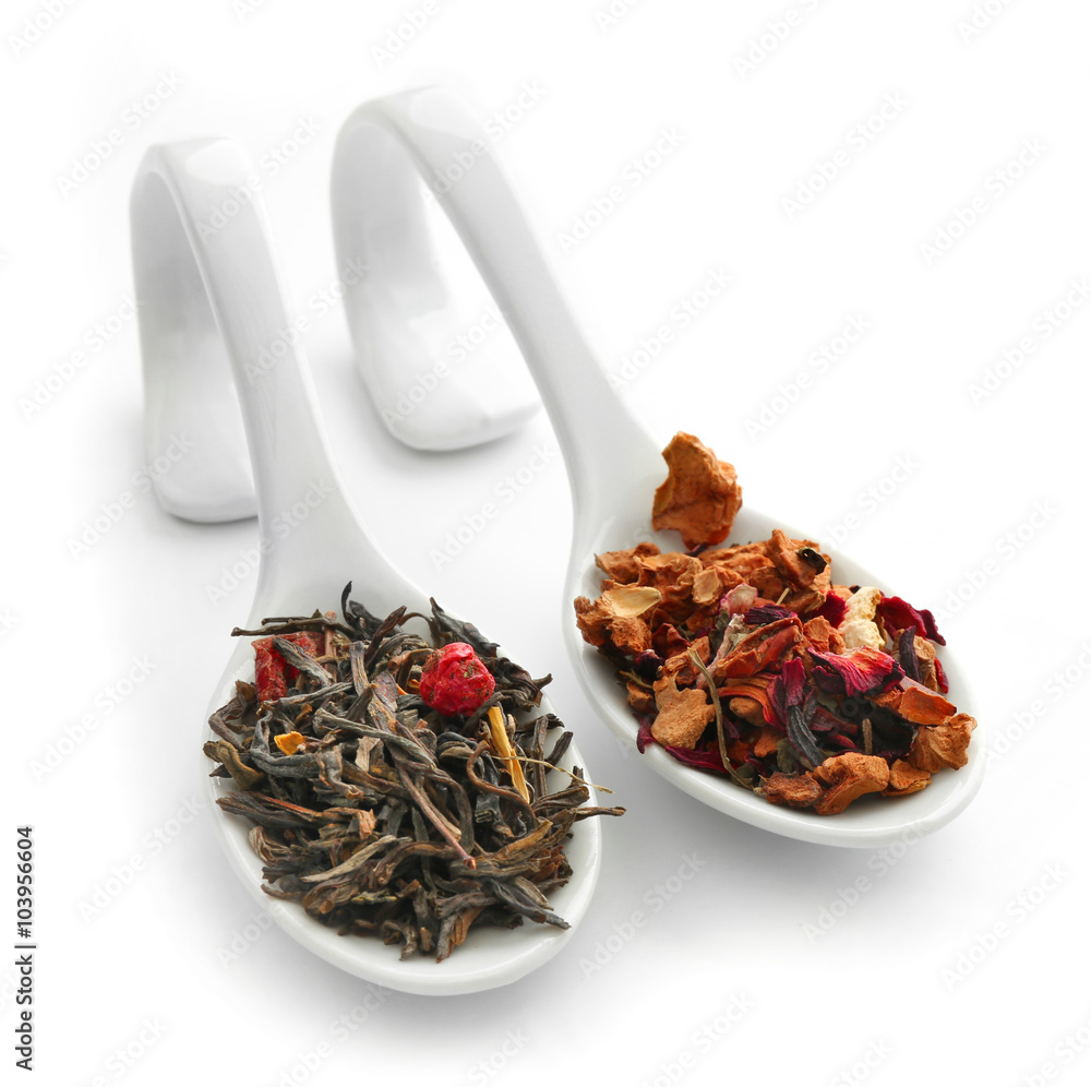 Different sorts of dry tea in ceramic spoons, isolated on white