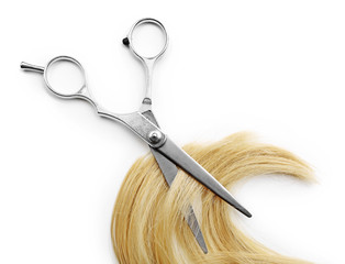 Wall Mural - Hairdresser's scissors with strand of blonde hair, isolated on white