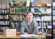 © Ermolaev Alexandr - male student in a library showing finger up