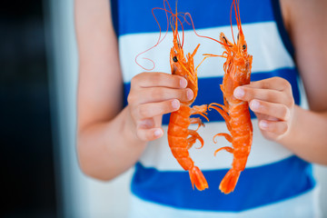 Close up of kid hands with cooked shrimps