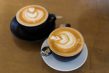 two cup of hot latte art coffee in black mug