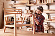 © mavoimages - Furniture designer sanding a wooden chair frame