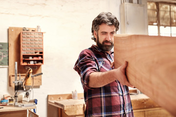 Wall Mural - Skilled craftsman inspecting a wooden plank for quality of cut 