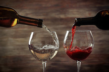 White And Red Wine Pouring In Glasses On Wooden Background