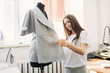 © lumenphotos - Young female fashion designer working on garment on dressmaker's model