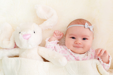 Wall Mural - Baby girl laying on her blanket with her stuffed bunny