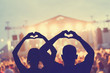 Couple enjoying the concert together while holding a heart-shape symbol with their hands.