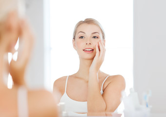 happy young woman looking to mirror at bathroom