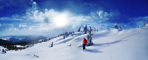 Skier skiing downhill in high mountains against sunset